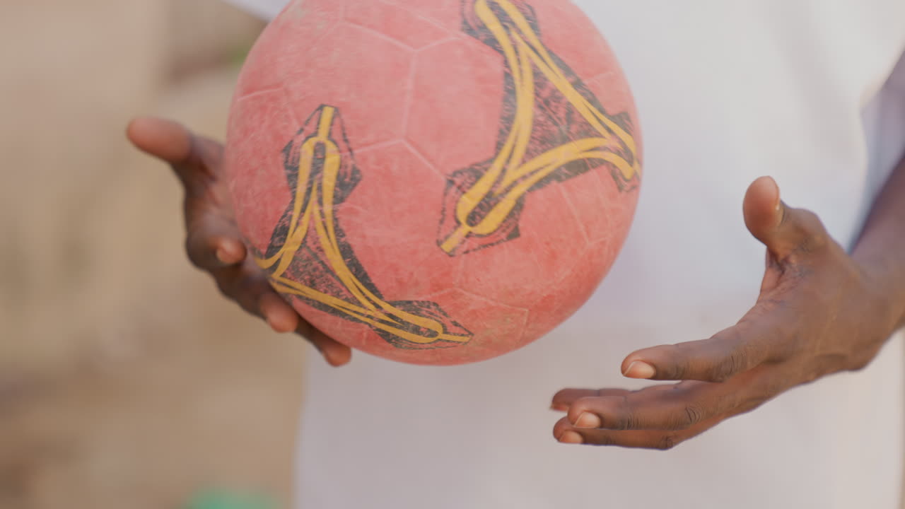 Homem africano foca em habilidades com a bola de futebol. Close-up de jogador dominando técnicas de futebol de rua. Cena de rua ensolarada retratando um jogador aspirante aprimorando suas habilidades de controle de bola.