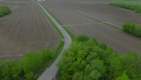 agricultural tractor driving in the road between the empty rural field