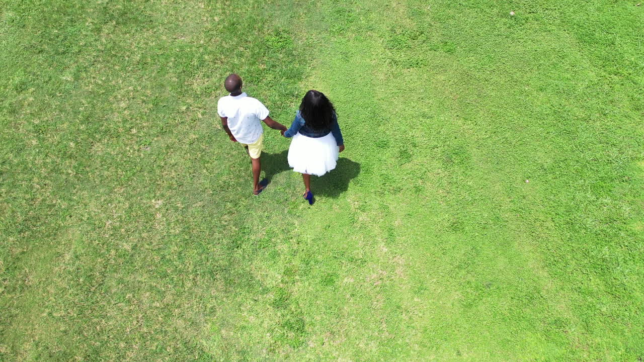 젊은 아프리카계 미국인 부부가 영화 4k 30fps에서 손을 잡고  ⁇ 은 잔디 ⁇ 에서  ⁇ 고 있습니다.