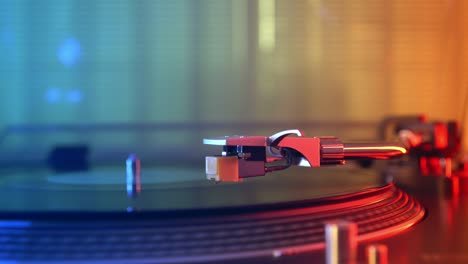 vinyl player turntable. a fragment of a rotating vinyl record, a stylus with a needle close-up. stopping a needle and a vinyl plate. macro. front view. blurred on a background of red and blue lights