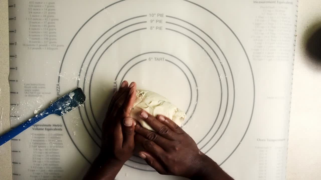 Overhead view of hands putting dough into a ball.