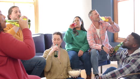 happy diverse male and female friends relaxing at home together and drinking beers