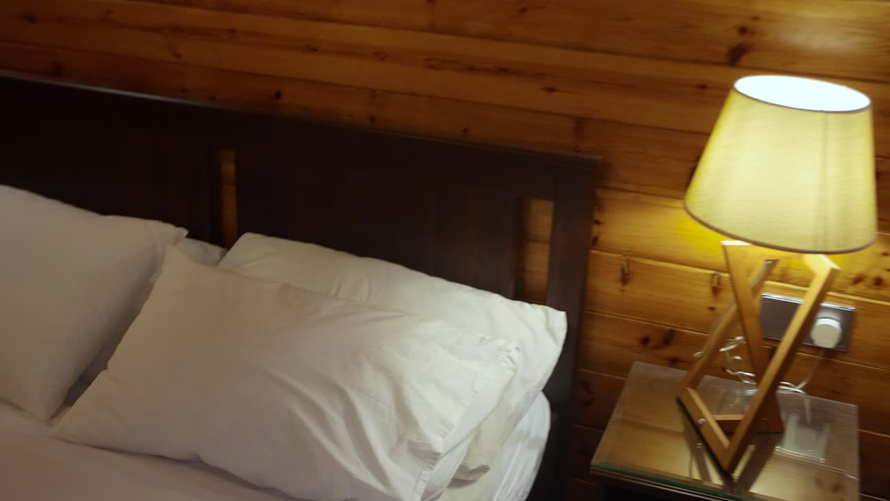 Aerial flying backwards into bedroom with double bed and lamp lit