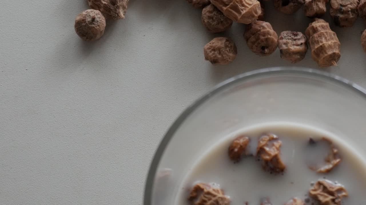 Glass of horchata chufa with tiger nuts on light background, healthy summer drink