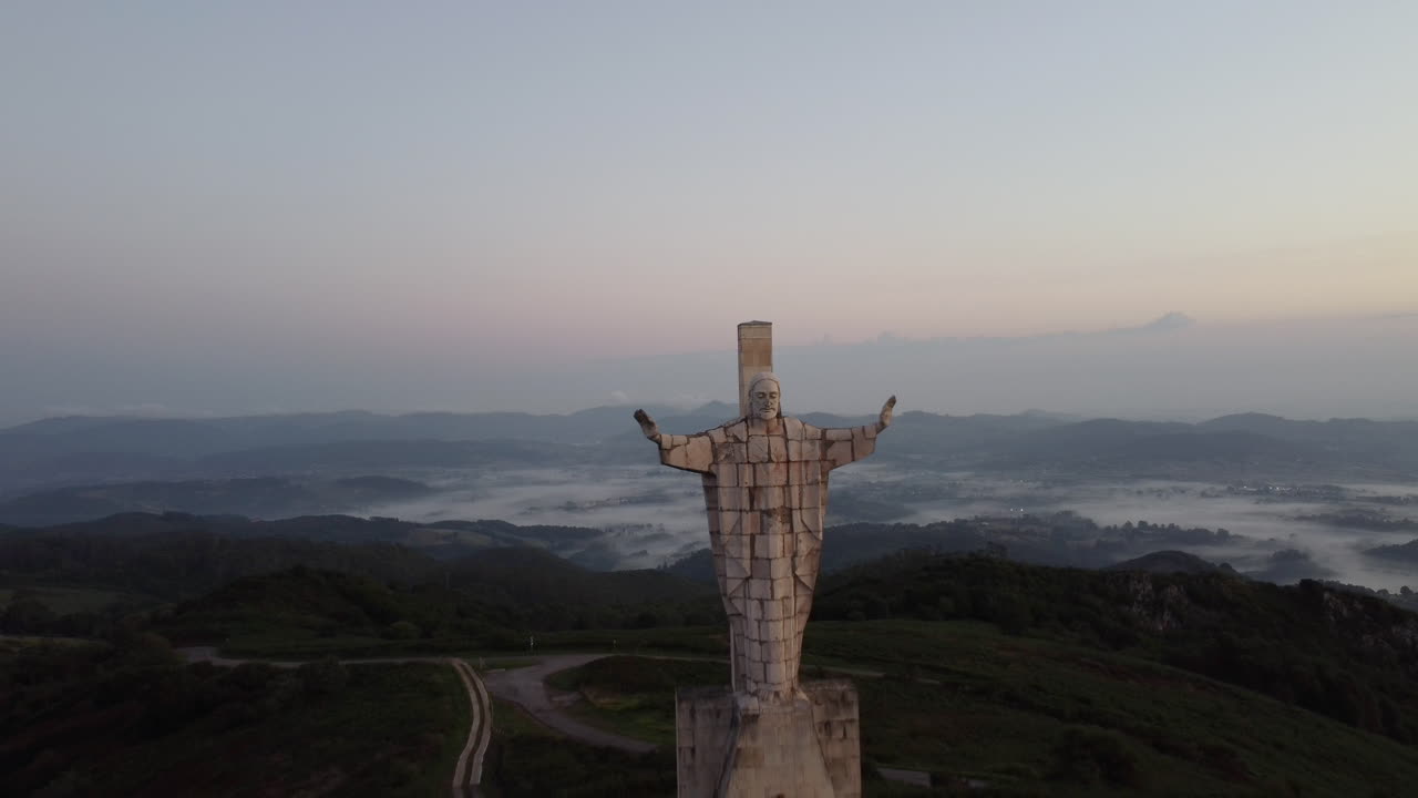 el dron se aleja de la vista de una estatua alta colocada en la cima de una montaña