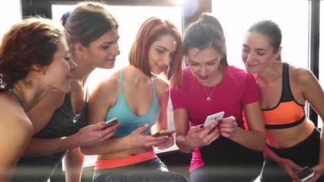 women friends in gym looking at phones