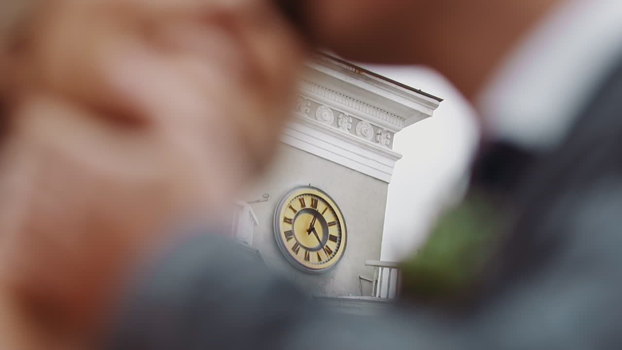 오래된 도시 탑에 있는 시계와 키스하는 신혼 부부