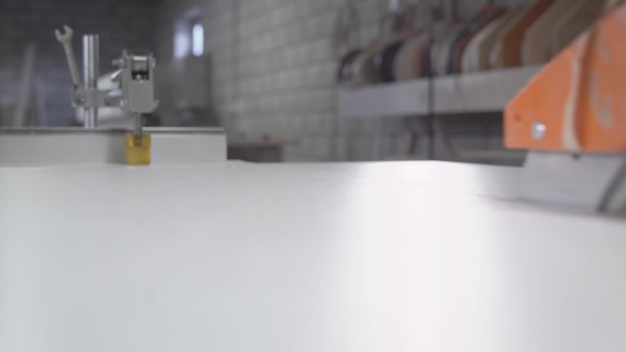 electrical saw is cutting long wooden panel in furniture factory, close-up view of worker hands and saw blade