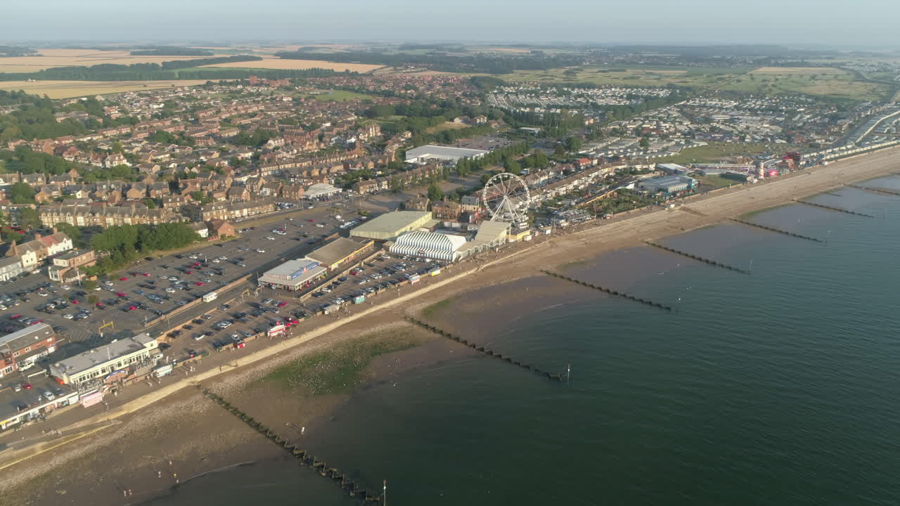 High Establishing Aerial Drone Shot Flying Forward Over Coastal Seaside Town New Hunstanton with Groynes along Sandy Beach and Ferris Wheel and Fun Fair with Calm Sea with Small Waves North Norfolk UK