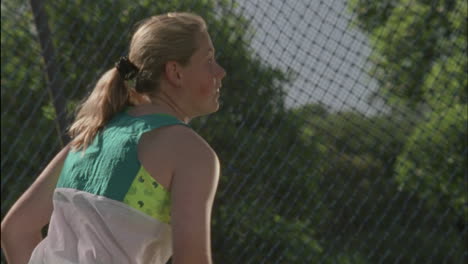 a woman leans down swings around and throws a ball then backs up and turns around