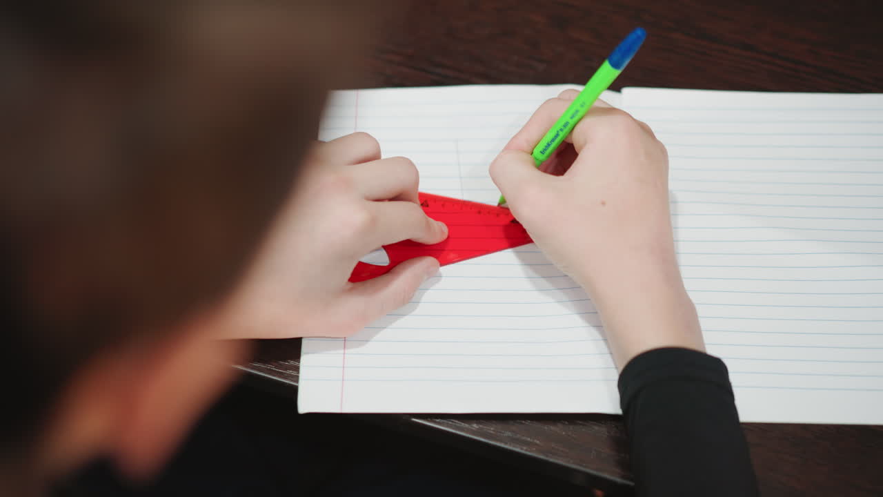 Young boy engaging in detailed writing exercise. Young child focusing on tracing patterns with green pen. Focused grandson carefully copying shapes onto dotted notebook using green pen