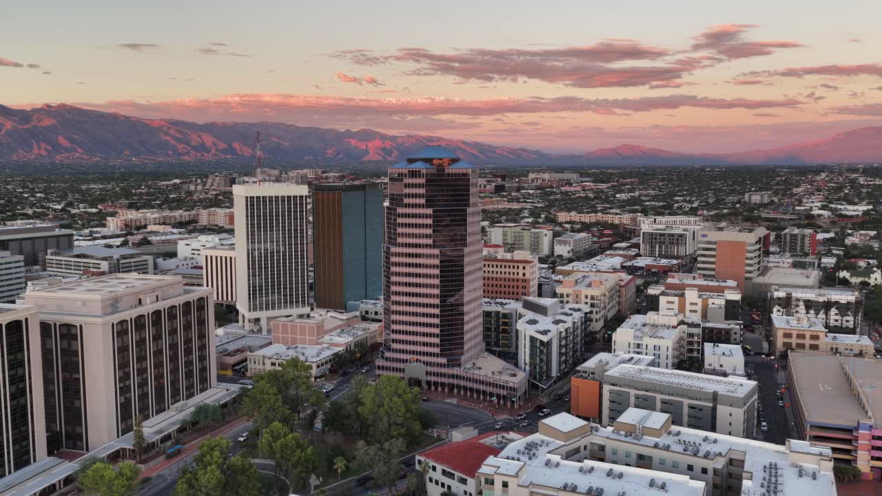 Circling drone push in towards downtown Tucson, Arizona at sunset with Catalina Mountains in background