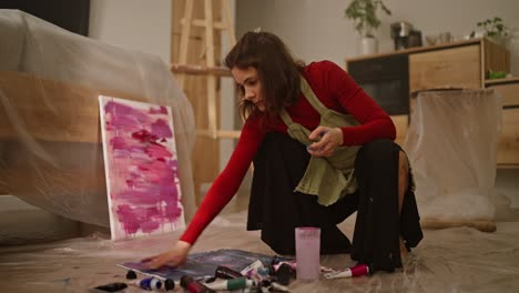 woman painting abstract art at home