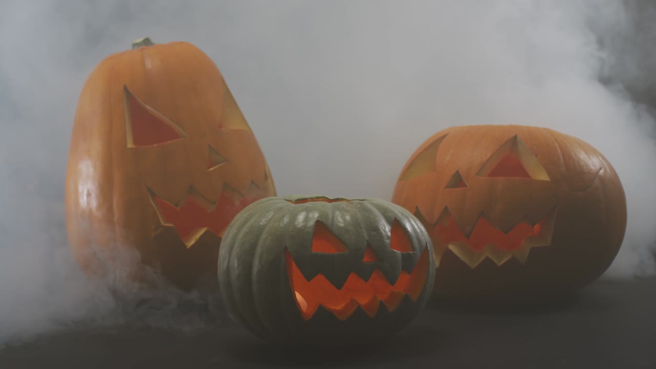 efecto de humo sobre múltiples cara aterradora tallada calabaza de halloween contra un fondo gris