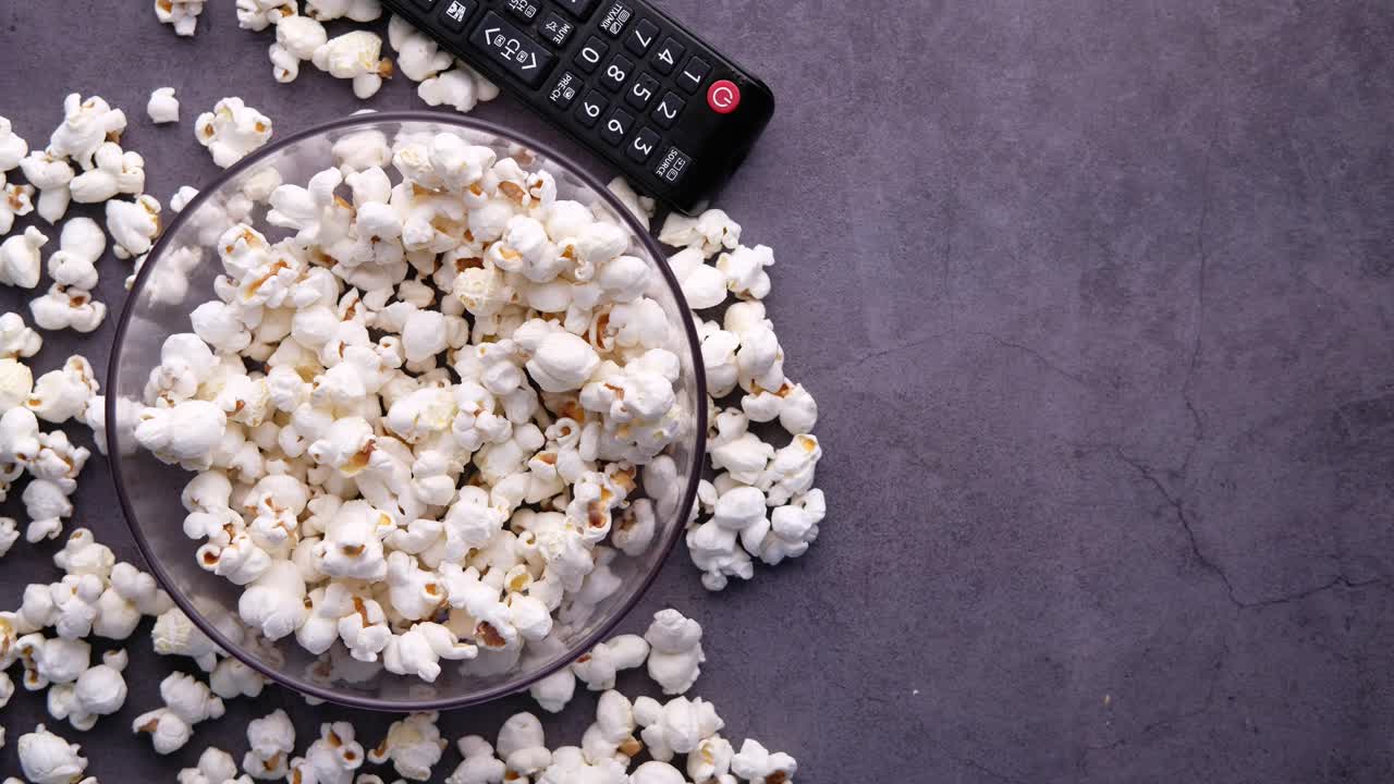 palomitas de maíz y control remoto de la tv en una superficie oscura