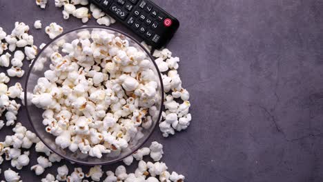 popcorn and tv remote on dark surface