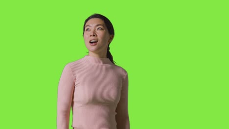 Studio-Shot-Of-Woman-With-Amazed-Expression-Looking-All-Around-In-VR-Environment-Against-Green-Screen