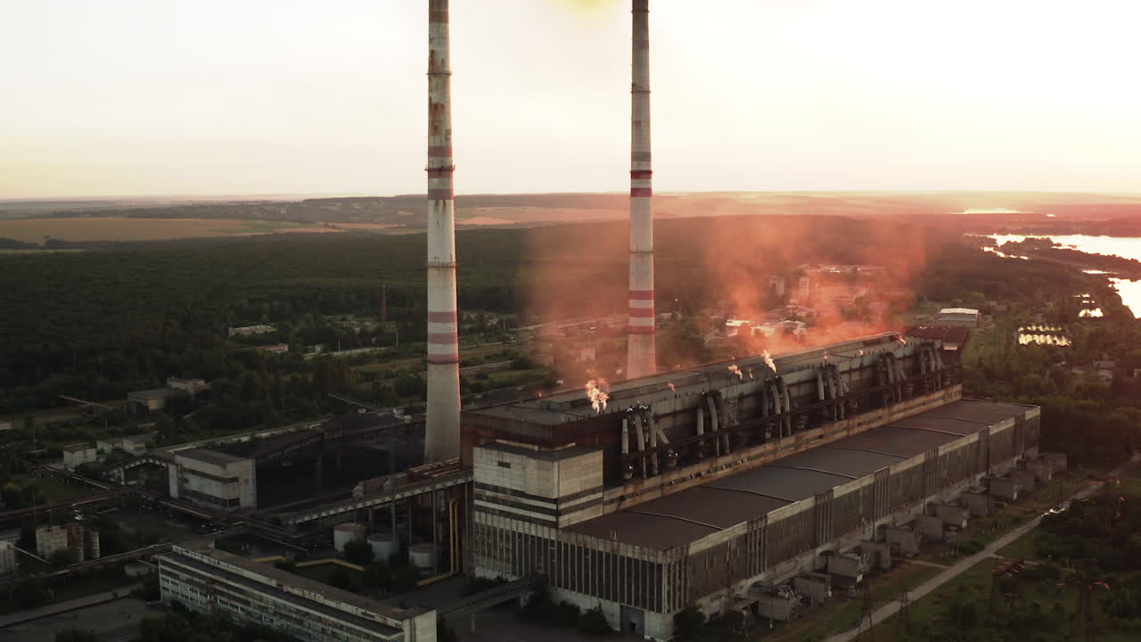 Dangerous manufacture with smoke at sunset. Industrial plant pollutes the air in the evening. Large chimneys of factory. Pollution the atmosphere. Aerial view.