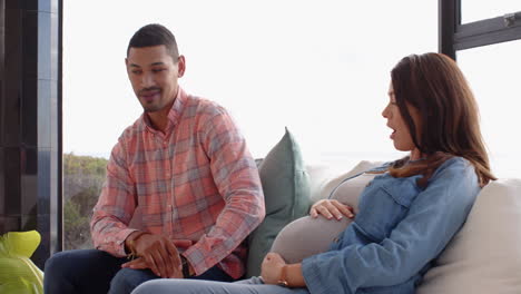 sitting on couch, pregnant woman talking with man, sharing happy moment