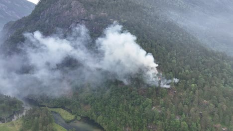 paralaje aéreo lento alrededor del humo de un incendio forestal que arde en una montaña en noruega