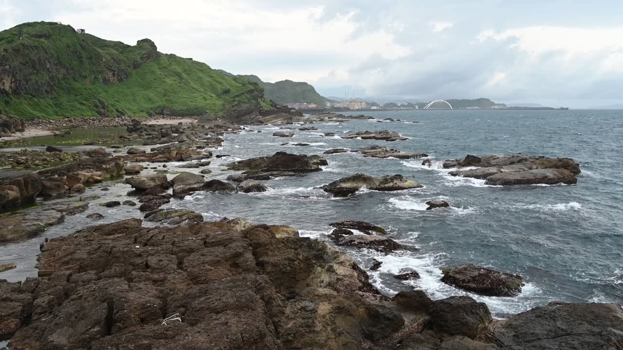 día de viento cerca de la costa, grandes olas salpicadas en las rocas, el cielo estaba nublado, en la ciudad de keelung, taiwán.