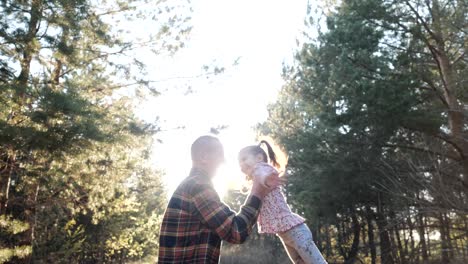 fun active games of happy old grandfather whirls little granddaughter in forest