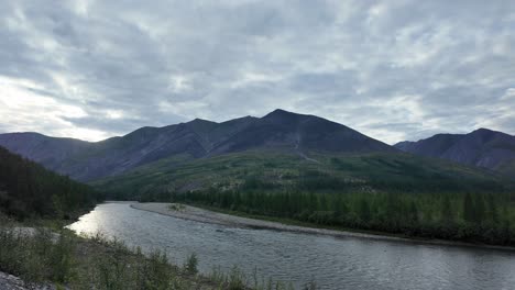 Descubra-La-Encantadora-Belleza-De-Yakutia-Mientras-El-Río-Brilla-Al-Anochecer,-Rodeado-De-Majestuosas-Montañas-Y-Exuberante-Vegetación,-Capturando-El-Arte-De-La-Naturaleza-En-Este-Remoto-País-De-Las-Maravillas.