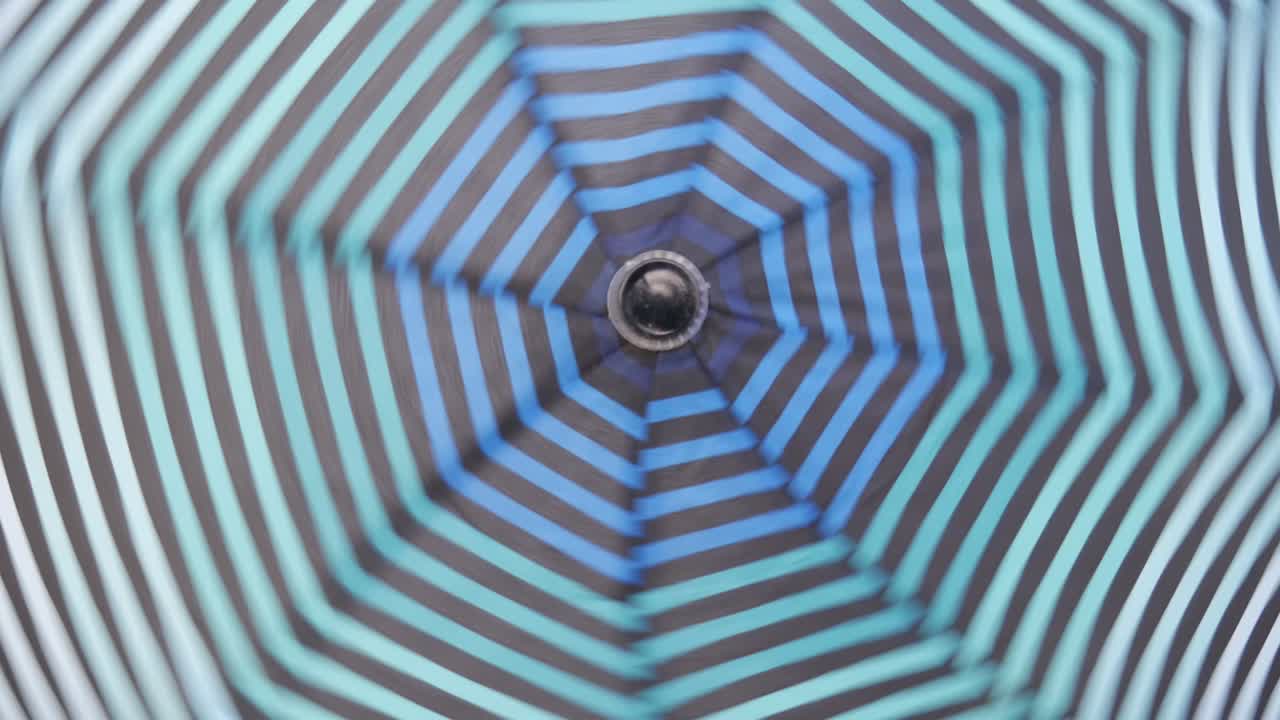 An open striped umbrella spinning around its axis.