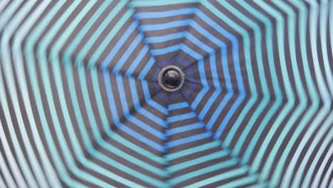 an open striped umbrella spinning around its axis.