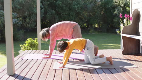 abuela y nieto de dos razas haciendo yoga, estirándose en la terraza, cámara lenta