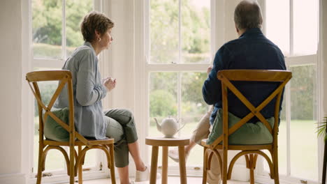 Old-couple-in-home,-tea-and-conversation