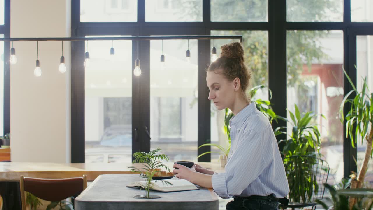 Donna che legge e beve caffè in un caffè
