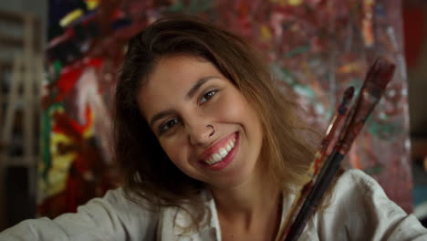 Cheerful-woman-looking-to-camera-indoors.-Smiling-painter-posing-in-art-studio.