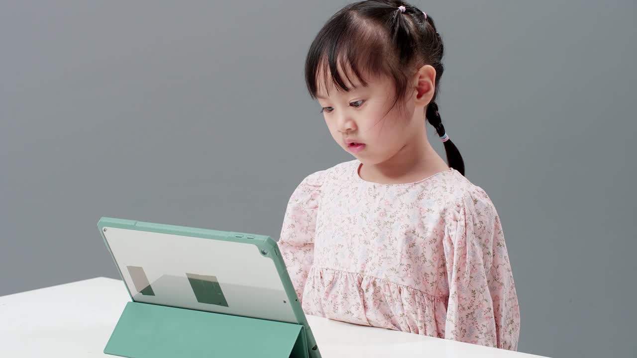 만화를 보기 위해 테이블 근처에 앉아 디지털 태블릿을 사용하는 어린이