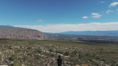 Man-Standing-on-Edge-Looking-Out-at-Vast-Arid-Mountainous-Landscape