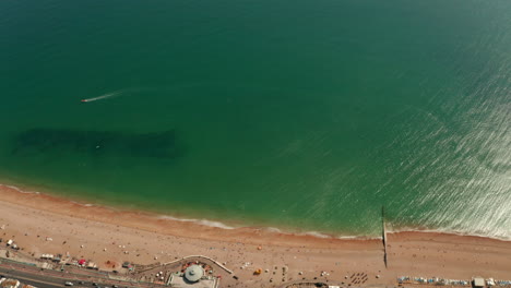 High-dolly-back-aerial-shot-from-the-sea-towards-Brighton-beach-and-town-centre