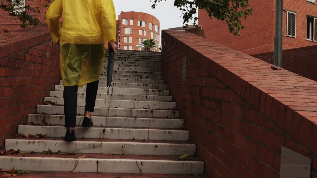 Business man tourist person with umbrella and raincoat on rainy european city street, lights reflecting, walking in Barcelona or Amsterdam during the rain