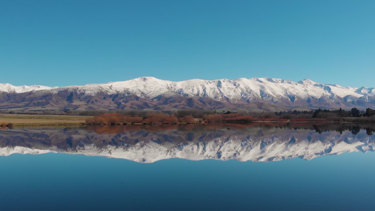 고요한 호수 위를 날아다니는 하얀 새 떼, 산맥과 푸른 하늘을 완벽하게 반영