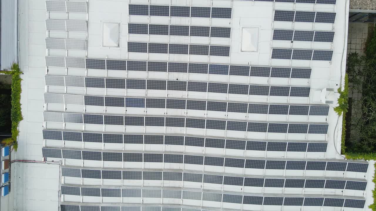 Beautiful top down aerial of photovoltaic solar panels covering the rooftop of an industrial building on a sunny day