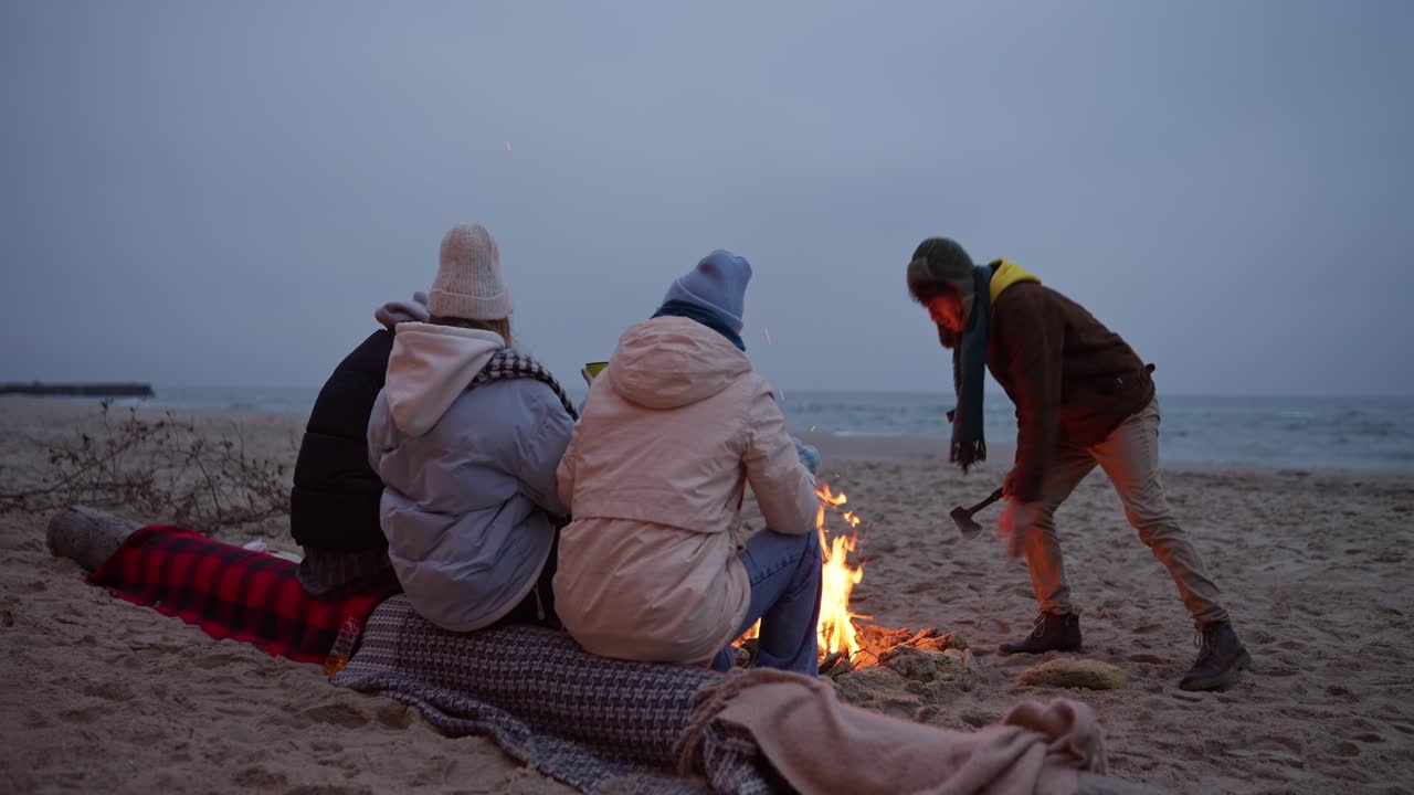 Friends enjoying a bonfire on the beach at sunset