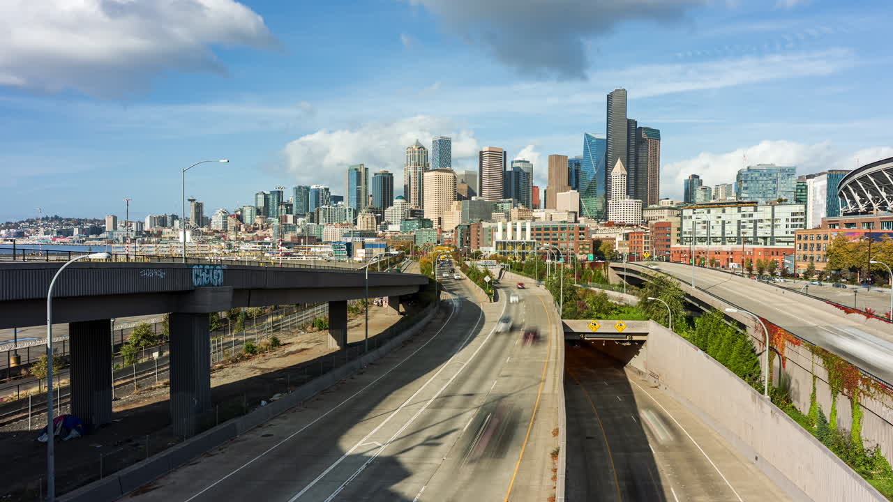 Timelapse dinamico del centro di Seattle con traffico scorrevole, strade sopraelevate e l'ingresso del tunnel SR 99 sotto l'iconico skyline in una giornata luminosa e parzialmente nuvolosa