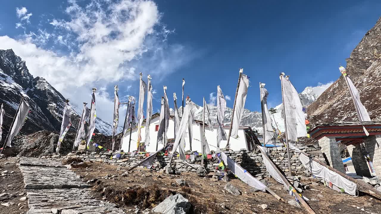 banderas de oración blancas en el viento frente al valle helado de kyanjin gompa