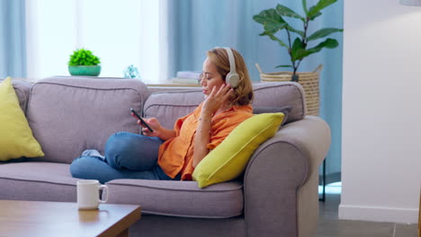 teléfono, auriculares de música y mujer en el sofá