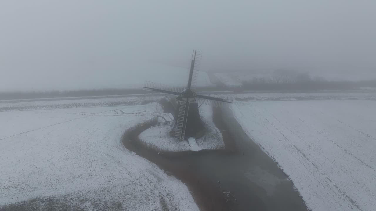 Vista aerea di Holwerd con il mulino a vento Miedenmolen, in inverno, che mostra un paesaggio panoramico pacifico nei Paesi Bassi.