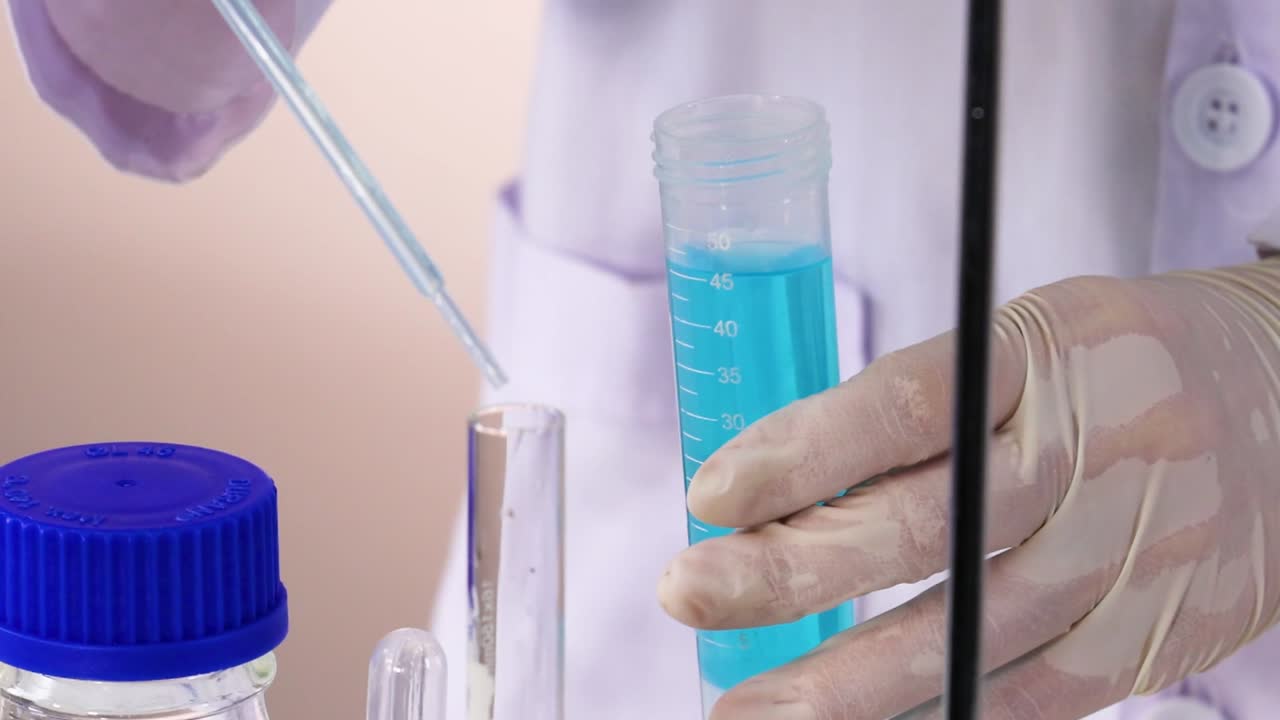 A scientist uses a pipette to transfer blue liquid into a test tube, showcasing precision in a laboratory setting.