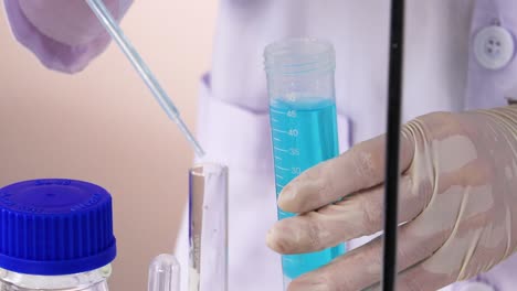 a scientist uses a pipette to transfer blue liquid into a test tube, showcasing precision in a laboratory setting.