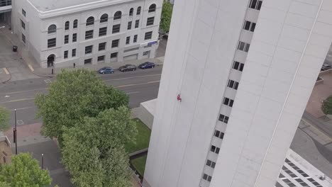 aerial, drone shot passing a man rope climbing on a skyscraper, on a overcast day, in washington state, usa