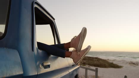 sección baja de la mujer relajándose con los pies en una camioneta en la playa 4k