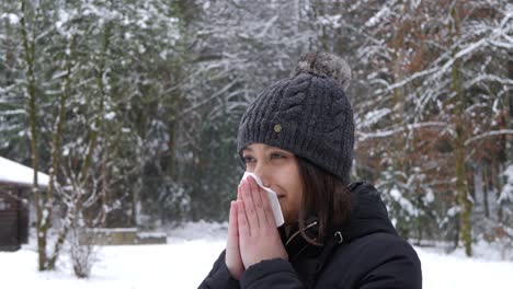 una joven asiática se suena la nariz en el frío bosque invernal, tiene un resfriado