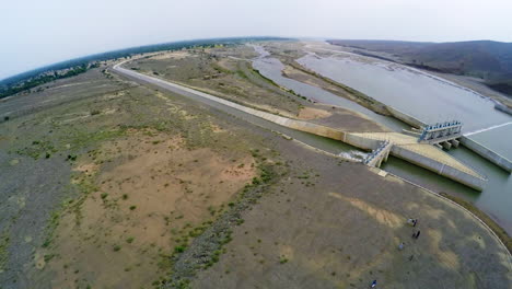 Aerial-view-of-spillway-of-a-dam,-A-van-and-some-visitors-are-there